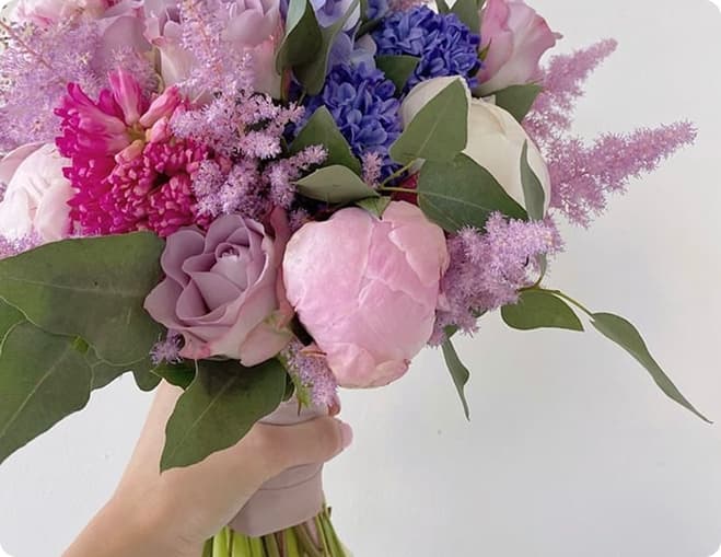 Рука, яка тримає букет з різних квітів